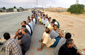 File - Palestinian men sit on a street in Gaza waiting at an Israeli check point.