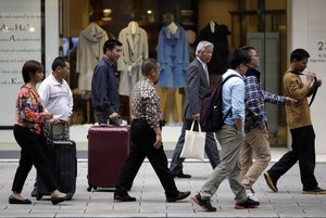 Shoppers walk at a shopping street in Tokyo, Tuesday, Nov. 17, 2015. (AP Photo/Eugene Hoshiko)