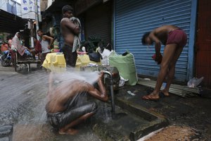 People take bath by a roadside water tap in the morning in Kolkata, India, Tuesday, June 4, 2019.