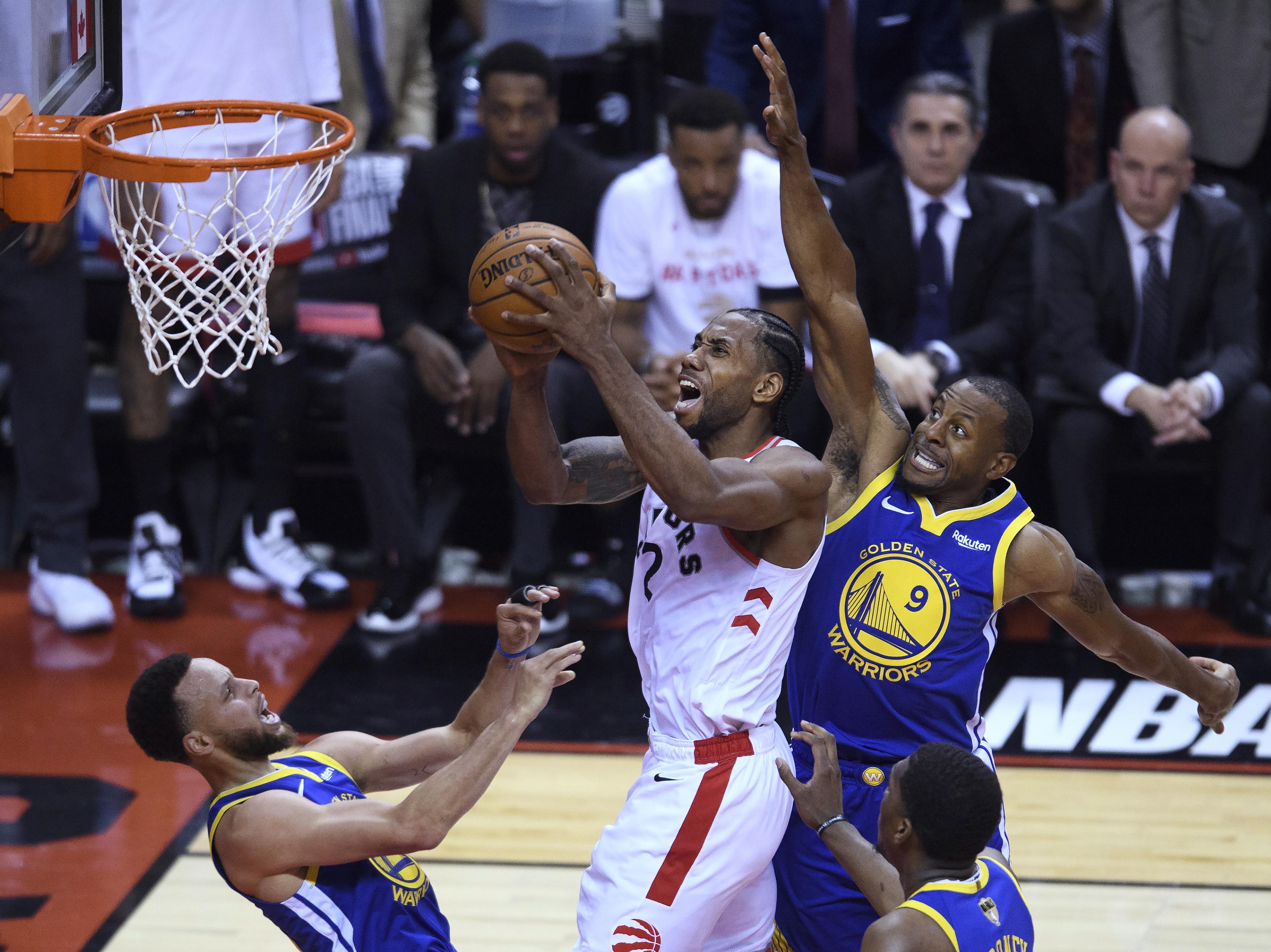 Kawhi Leonard knocks down Stephen Curry as he drives past Andre Iguodala during game one of the NBA Finals.