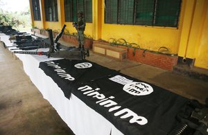 A Philippine Marine guards the display of high-powered firearms, ammunitions, uniforms and black ISIS-style flags which were recovered from Muslim militants Tuesday, May 30, 2017