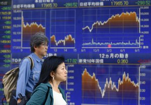 People walk past an electronic stock indicator of a securities firm in Tokyo, Monday, Sept. 14, 2015. Asian stocks were mostly lower Monday after China reported weak factory output and as investors looked ahead to a U.S. Federal Reserve decision this week on whether to raise interest rates. Japan's Nikkei 225 fell 1.6 percent to 17965.70. (AP Photo/Shizuo Kambayashi)