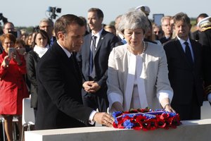 British Prime Minister Theresa May  and French President Emmanuel Macron, left, lay a wreath of flowers at the commemorative first stone for a British memorial during a Franco-British ceremony to mark the 75th anniversary of D-Day landings at Ver-Sur-Mer, Normandy, Thursday, June 6, 2019.