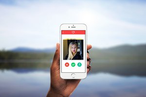 A cell phone against a picturesque background with a dating app Tinder