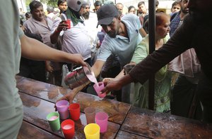 Volunteers offer flavored water to commuters as city witnesses an intense heat wave, in New Delhi, India, Friday, June 7, 2019