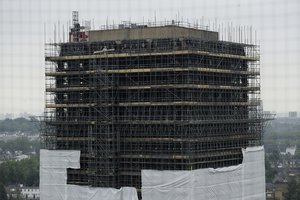 Work is carried out on the scaffold covered burnt out Grenfell Tower, almost one year on from the fire that killed 72 people, in London, Wednesday, May 30, 2018.