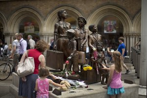 People look at flowers laid in memory of Britain's Sir Nicholas Winton on German-born Jewish sculptor Frank Meisler's "Kindertransport" (German for children transport) memorial statue outside Liverpool Street Station in London, Thursday, July 2, 2015.