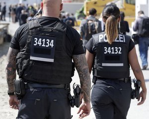 A federal police officer sports a tattoo when guarding the meeting o French President Emmanuel Macron with German Chancellor Angela Merkel at the reconstruction site of the Berlin Palace in Berlin, Germany, Thursday, April 19, 2018.