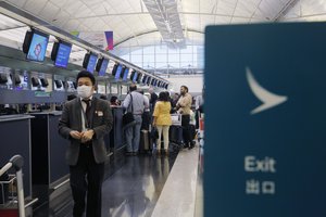 In this March 26, 2019 photo, passengers wait at the check-in counter of Cathay Pacific Airways at the Hong Kong International Airport.