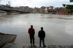 People take a look at the rising waters of Jehlum river in Srinagar, India , Thursday 25, June 2015.