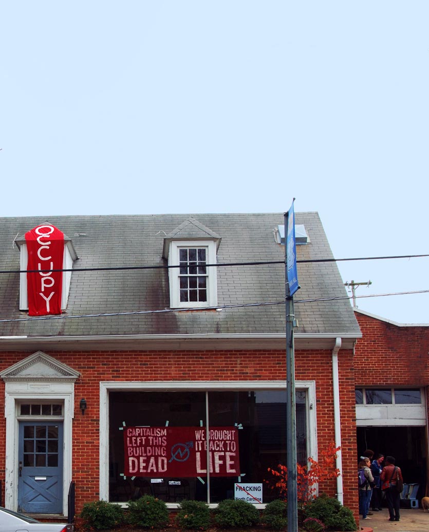 an abandoned building, now occupied, with protest banners in the window, being used as community organizing location