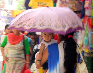 File - A mother and young child use an umbrella as protection from the scorching heat in Jammu, Jammu and Kashmir State, India, 25th april 2016.