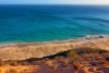 Looking from the top of a dune down onto a beach, where there are hundreds of turtle tracks, then the ocean.