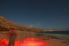 A small group of women walking along a beach at night.