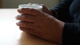 A woman's hands hold a cup of tea on a table