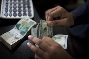 A Pakistani money changer counts US dollar bills in Islamabad, Pakistan, Friday, Nov. 30, 2018.