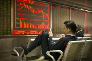 A Chinese investor uses his smartphone as he monitors stock prices at a brokerage house in Beijing, Friday, March 23, 2018.