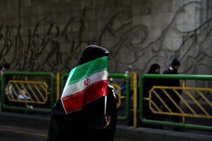 FILE - In this Thursday, Feb. 11, 2016 file photo, an Iranian woman holds the national flag during a rally commemorating the 37th anniversary of the Islamic revolution, in Tehran, Iran.