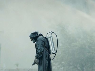 A man in a hazmat suit walks through fog