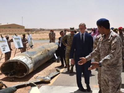 Men gesture toward the wreckage of what looks to be an aircraft, drone, iran