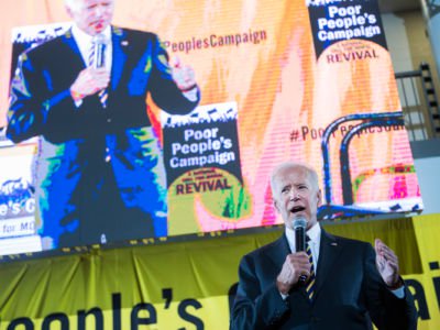 Joe Biden speaks in front of a loudly colored display screen also displaying his likeness