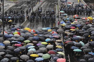 Protesters holding umbrellas face off police officers in anit-riot gear in Hong Kong on Monday, July 1, 2019.