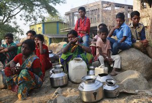 In this April 12, 2016 photo, people wait to fill their vessels with water at a communal tap in Kukse Borivali, 85 kilometers (53 miles) north-east of Mumbai, India.