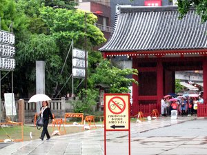 The rain has kept most visitors under the shade, while a woman walks along with an umbrella inside temple grounds in Tokyo, Japan. Taken on May 2014.