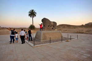 People stand near the Lion of Babylon at the archaeological site of Babylon, Iraq, Friday, July 5, 2019