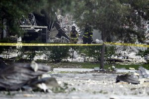 Firefighters walk through the remains of a building after an explosion on Saturday, July 6, 2019, in Plantation, Fla.