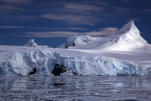 A tidewater glacier on the Antarctic coast, with a sharply peaked mountain behind