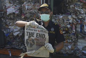 Indonesian customs officers show off the front of a foreign newspaper among waste found in a container at the Tanjung Perak port in Surabaya, East Java, Indonesia, Tuesday, July 9, 2019.