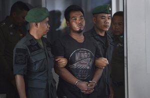 Thai suspect Ronnakorn Romruen, 23 years old, is escorted by police as he arrives at the Koh Sichang police station in Chonburi province, Thailand, Monday, April 9, 2019. Ronnakorn has been charged with the rape and murder of a German tourist on the island of Sichang.