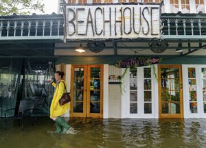 Aimee Cutter, the owner of Beach House restaurant, walks through water surge from Lake Pontchartrain on Lakeshore Drive in Mandeville, La., ahead of Tropical Storm Barry, Saturday, July 13, 2019.