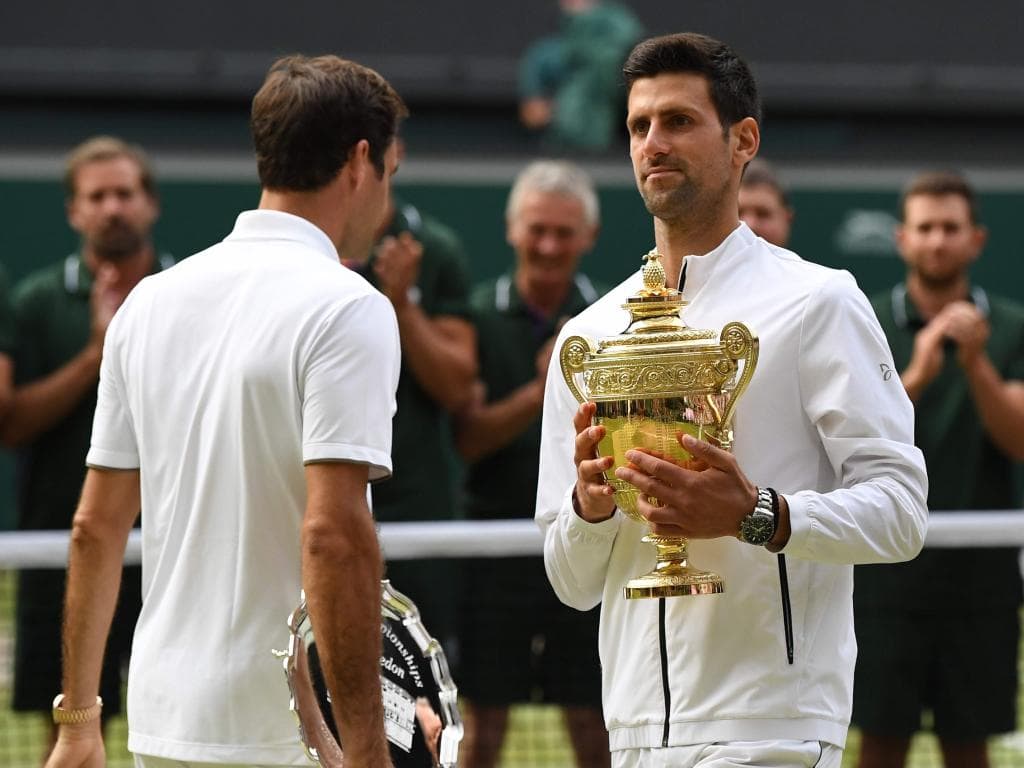 Serbia's Novak Djokovic (R) holds the winner's trophy and passes runner up Switzerland's Roger Federer (L) during the presentation at the end of the men's singles final on day thirteen of the 2019 Wimbledon Championships at The All England Lawn Tennis Club in Wimbledon, southwest London, on July 14, 2019. (Photo by Ben STANSALL / AFP) / RESTRICTED TO EDITORIAL USE