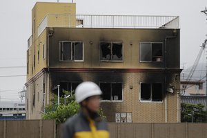 A security guard stands near the Kyoto Animation Studio building destroyed in an attack, Friday, July 19, 2019, in Kyoto, Japan.