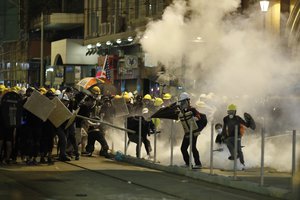 Protesters react to teargas as they confront riot police officers in Hong Kong on Sunday, July 21, 2019.