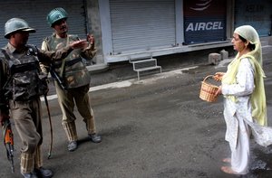 Indian paramilitary troops stop a kashmiri muslim woman During a  curfew in Srinagar India, on 14, Sep 2010. Curfew was today extended to all major towns of the Kashmir Valley as a precautionary measure after violent clashes left 17 people dead and over 70 injured, official sources said.