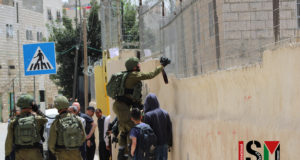 Soldier standing on another soldier taking pictures into a school