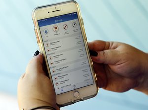 In this Tuesday, Aug. 1, 2017 photo, Jen Vargas checks out an AT&T app on her cell phone at her home in Orlando, Fla. The app helps locate and block fraudulent calls although some robocalls still get through. (AP Photo/John Raoux)