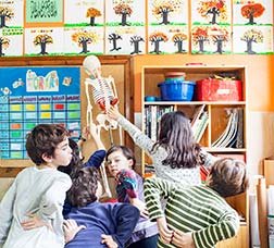 Alumnes jugant amb un esquelet dins una aula.