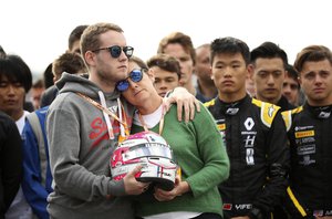 The mother and brother of Anthoine Hubert hold the helmet of Anthoine Hubert during a moment of silence at the Belgian Formula One Grand Prix circuit in Spa-Francorchamps, Belgium, Sunday, Sept. 1, 2019.