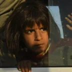 A young Syrian girl peers out the window of one of the buses bring 784 Syrian refugees to Bardarash Refugee Camp in Iraqi Kurdistan.  