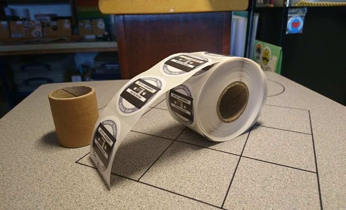 An image of a roll of stickers with the campaign logo which is a circular badge with a cassette tape on it