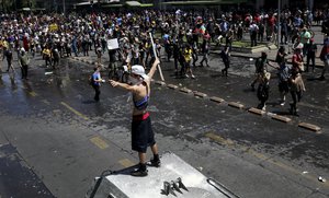 A demonstrator stands on a police armored vehicle during a protest in Santiago, Chile, Wednesday, Oct. 23, 2019