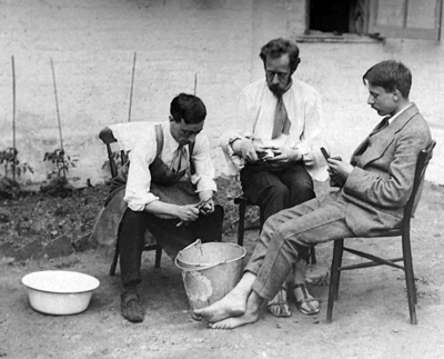 three men peeling potatoes in garden, around 1917
