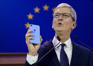 Apple CEO Tim Cook holds up an iPhone as he speaks during a data privacy conference at the European Parliament in Brussels, Wednesday, Oct. 24, 2018