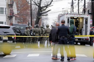 Police officers gather nearby the scene following reports of gunfire in Jersey City, N.J.