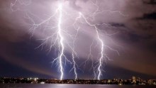 Lightning strikes over the Swan River as a thunderstorm hits Perth.