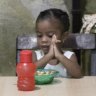 Children eat at a soup kitchen as adults wait to be served in the Petare slum, in Caracas, Venezuela, last week.